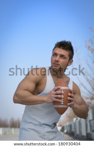 Muscular american football player ready to throw ball in hand. Outdoors shot
