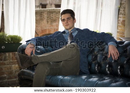 Attractive young man sitting on elegant sofa in luxurious home