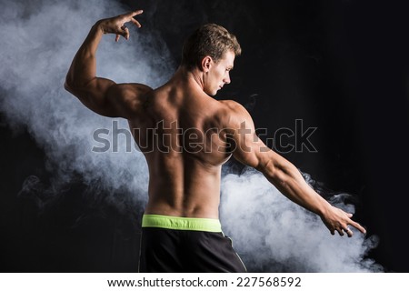 Attractive shirtless muscular man striking a pose, showing back, shoulders and triceps