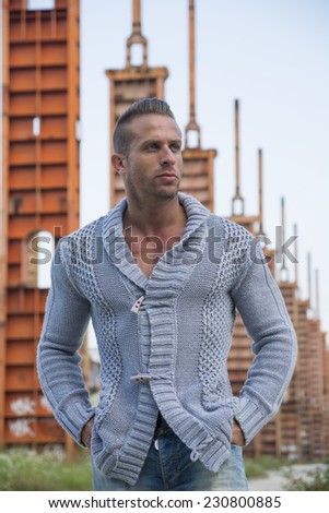 Handsome muscular blond man standing in city setting or former industrial environment