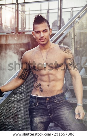 Handsome fit athletic shirtless young man in city setting on metal stairc steps