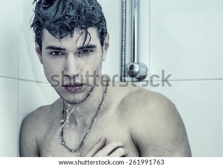 Close up Attractive Young Bare Muscular Man Taking Shower with One Hand on his Chest and Looking at the Camera.