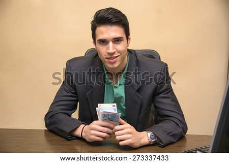 Close up Smiling Young Businessman, Sitting at his Worktable, Counting Cash on Hand