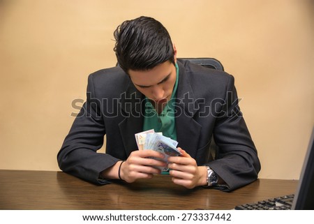 Close up Serious Young Businessman, Sitting at his Worktable, Counting Cash on Hand Seriously.