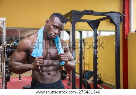 Hunky muscular black bodybuilder working out in gym, resting after exercise