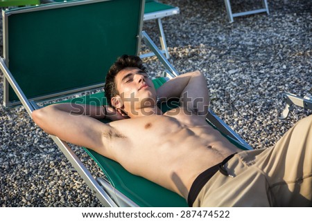 Shirtless Young Man Drying Off in Hot Sun, Muscular Man Wearing Bathing Suit  Sunbathing on Beach Lounge Chair on Grass