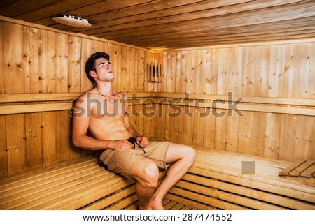 Young Handsome Muscular Man Relaxing in Sauna, Sitting on Wooden Bench