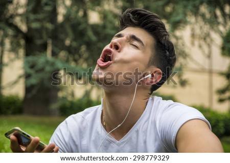 Close up Young Man Singing Out Loud While Listening to his Favorite Music Using Headphone at the Park.