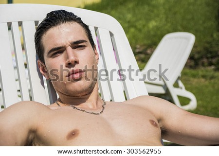 Shirtless Young Man Drying Off in Hot Sun, Muscular Man Wearing Bathing Suit and Sunglasses Sunbathing on Lounge Chair on Grass