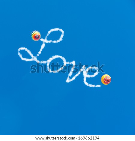 Love is in the air. Two hot air balloons in blue sky and Love word with cloudy text effect.