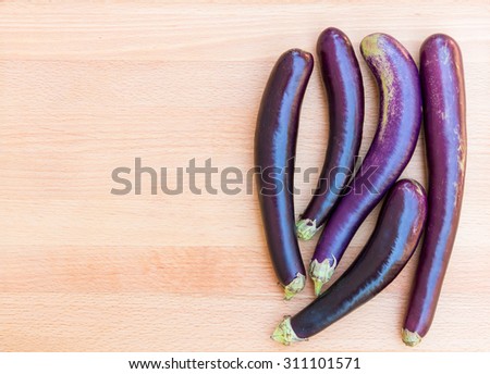 Purple japanese eggplants on wooden cutting board.