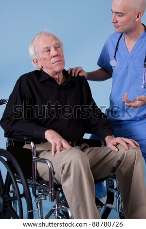 Doctor or nurse is talking to elderly patient in wheel chair.