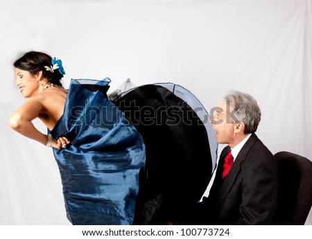 Attractive, mature couple in romantic mood, she is flipping her long dress up so he can get a peek underneath.