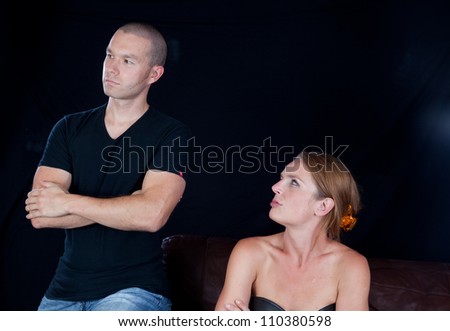 Couple together and angry at each other, he has his arms crossed and she glares at him and he looks away