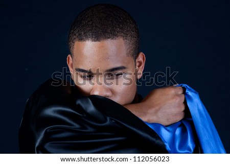 Cute black man with a black cape, looking right over the shiny material