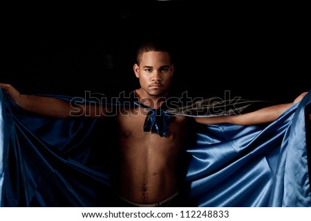 Young black man playing with a cape with blue satan on the inside of the cape