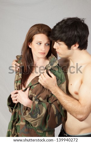 Romantic couple, he is topless and she is wearing a military jacket with nothing underneath, in loving moments