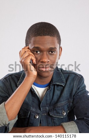 Handsome black man sitting with his head in his hand, looking frustrated or depressed as he stars at the camera