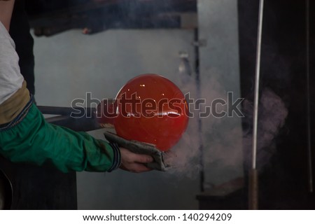 Glass blower, working with his glass creation shaping and quinching the heat