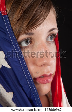 Pretty brunette woman with a flag of the United States drawn around her, looking to the right with a thoughtful expression