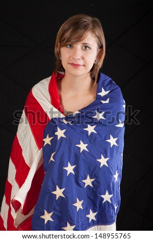 Pretty woman wrapped in a flag of the United States, and a serious expression, looking at the camera with a hint of a serious smile
