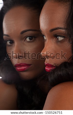 Sexy black woman in black shirt, looking into a mirror showing her own reflection