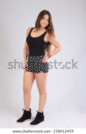 pretty black woman in shorts  sitting on a wooden stool and smiling at the camera