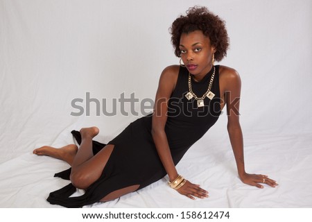 pretty black woman in shorts  sitting on a wooden stool and smiling at the camera