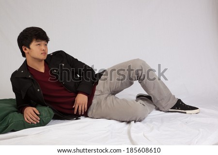 Asian man laying down and looking to the right thoughtfully and seriously