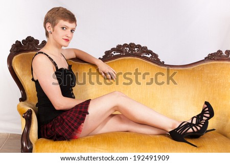 Pretty short haired, Caucasian woman reclining casually on a couch   and  a friendly look for the camera