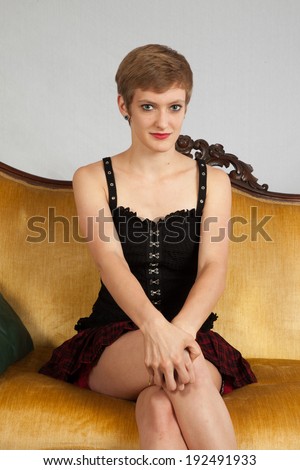 Pretty short haired, Caucasian woman sitting on a couch with her legs crossed and her hands on her knee,  a friendly look for the camera