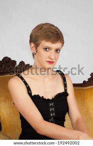 Pretty short haired, Caucasian woman sitting on a couch   and  a friendly look for the camera