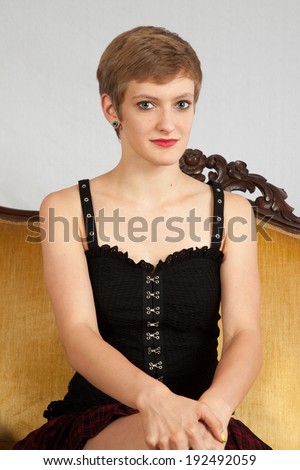 Pretty short haired, Caucasian woman sitting on a couch with her legs crossed and her hands on her knee,  a friendly look for the camera