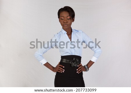 Pretty black woman in white blouse, standing and looking at the camera with a thoughtful expression