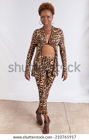 Pretty Black woman in a leopard print outfit, standing and looking at the camera with a happy smile