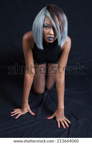 Beautiful black woman in black lingerie, looking thoughtfully at the camera kneeling down