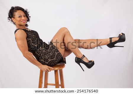 Pretty Black woman balanced on a stool and kicking up her legs