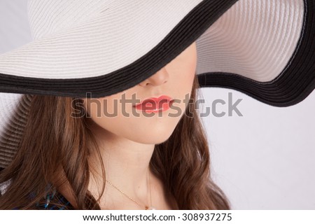 Pretty Caucasian woman in white hat with black rim and bow, looking thoughtfully