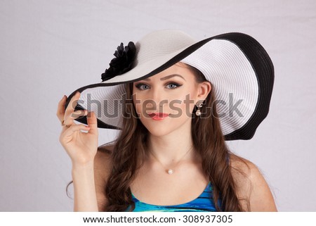 Pretty Caucasian woman in white hat with black rim and bow, looking happy