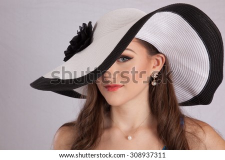 Pretty Caucasian woman in white hat with black rim and bow, looking happy