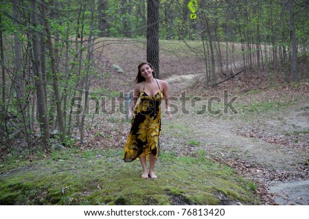 Lovely lady ina yellow dress standing in woods, by a stream