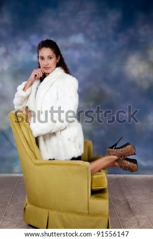 Pretty caucasian woman kneeling backwards in a chair with a playful, smile