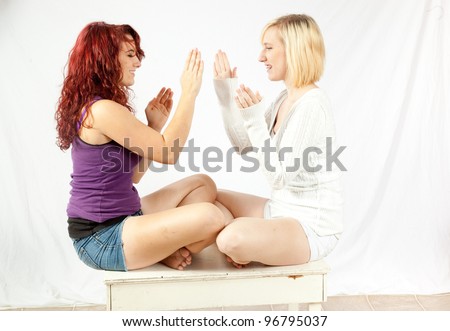 Two teenage sisters playing patty-cake together and having fun