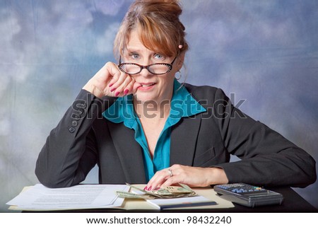Businesswoman frustrated with accounting, paper, and money before her