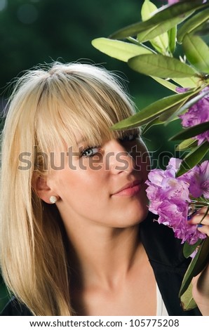 Young blonde woman smelling lilac flower in the park