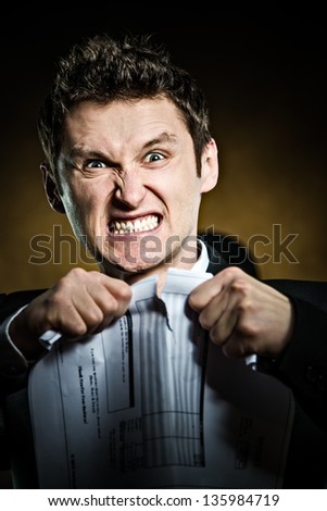 Angry businessman tearing document in pieces