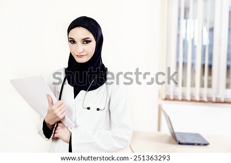 Muslim female doctor standing and holding medical files at the hospital