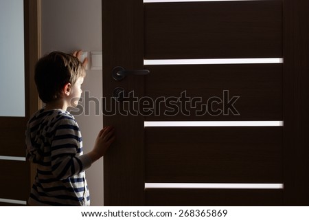 Little boy opens the door to the room by night