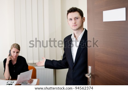 Office life scene. Young businessman invites to his office. Place for own text on doors plate