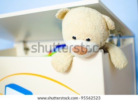 Teddy bear escaping from toy box.